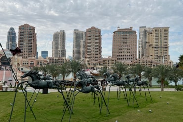 Metal horses with tall buildings in the background